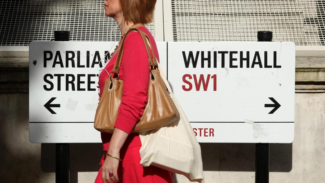 Woman in a red dress walking in front of a sign for Parliament Street and Whitehall.