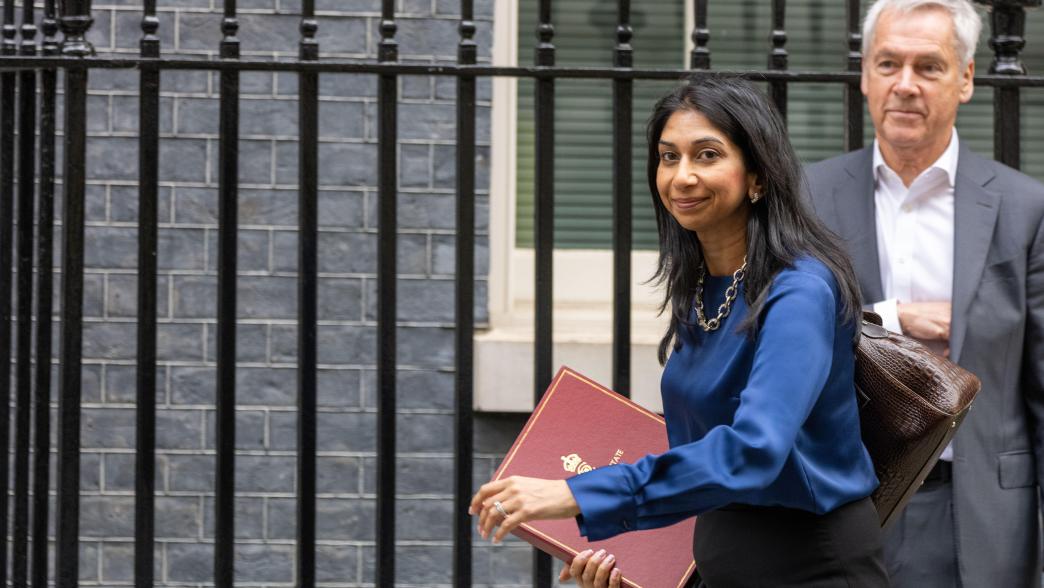 Suella Braverman, home secretary, walking down Downing Street. She is wearing a blue blouse and black skirt. In her hand is a ministerial folder.